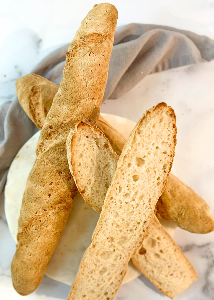 Three gluten-free baguette pieces displayed on a white plate, emphasizing their light color and artisanal quality